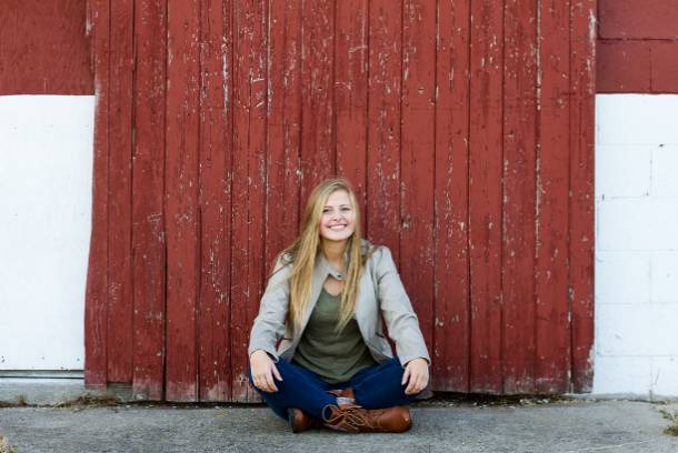 Kendall Keeler  sitting in front of a red barn door